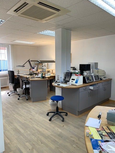 Ein Raum mit vielen Schreibtischen und einem blauen Hocker