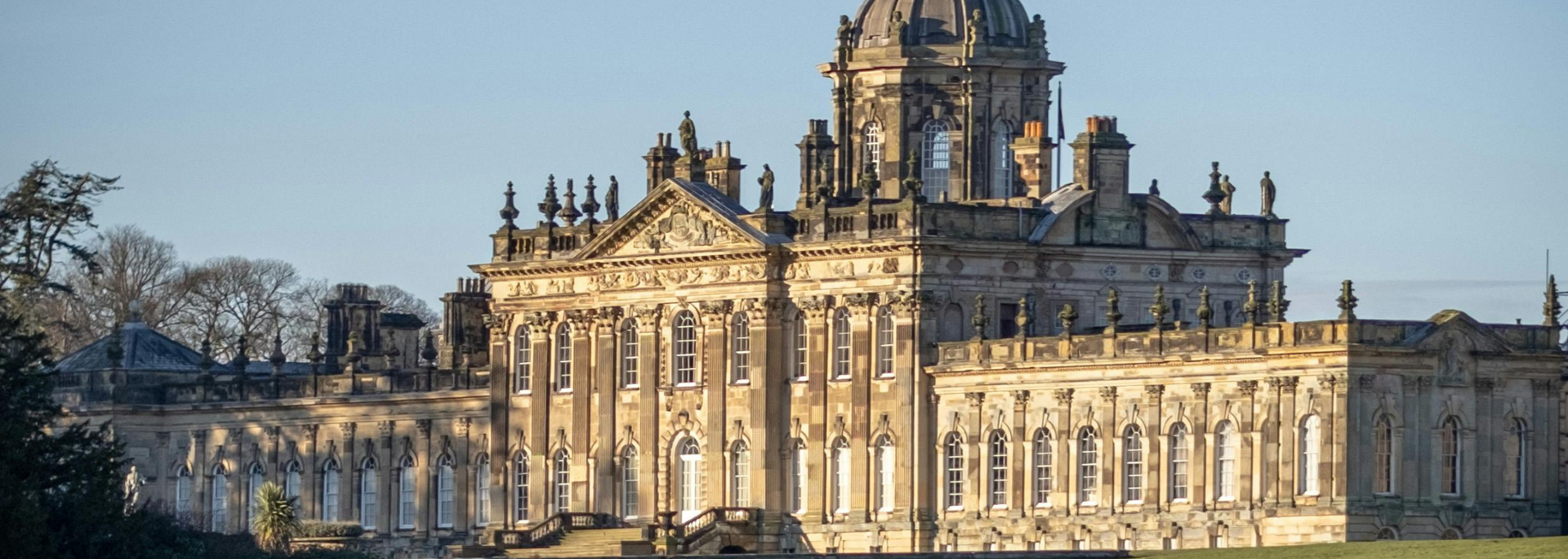 A large, ornate, light-colored building with multiple columns, windows, and a domed roof under a blue sky.