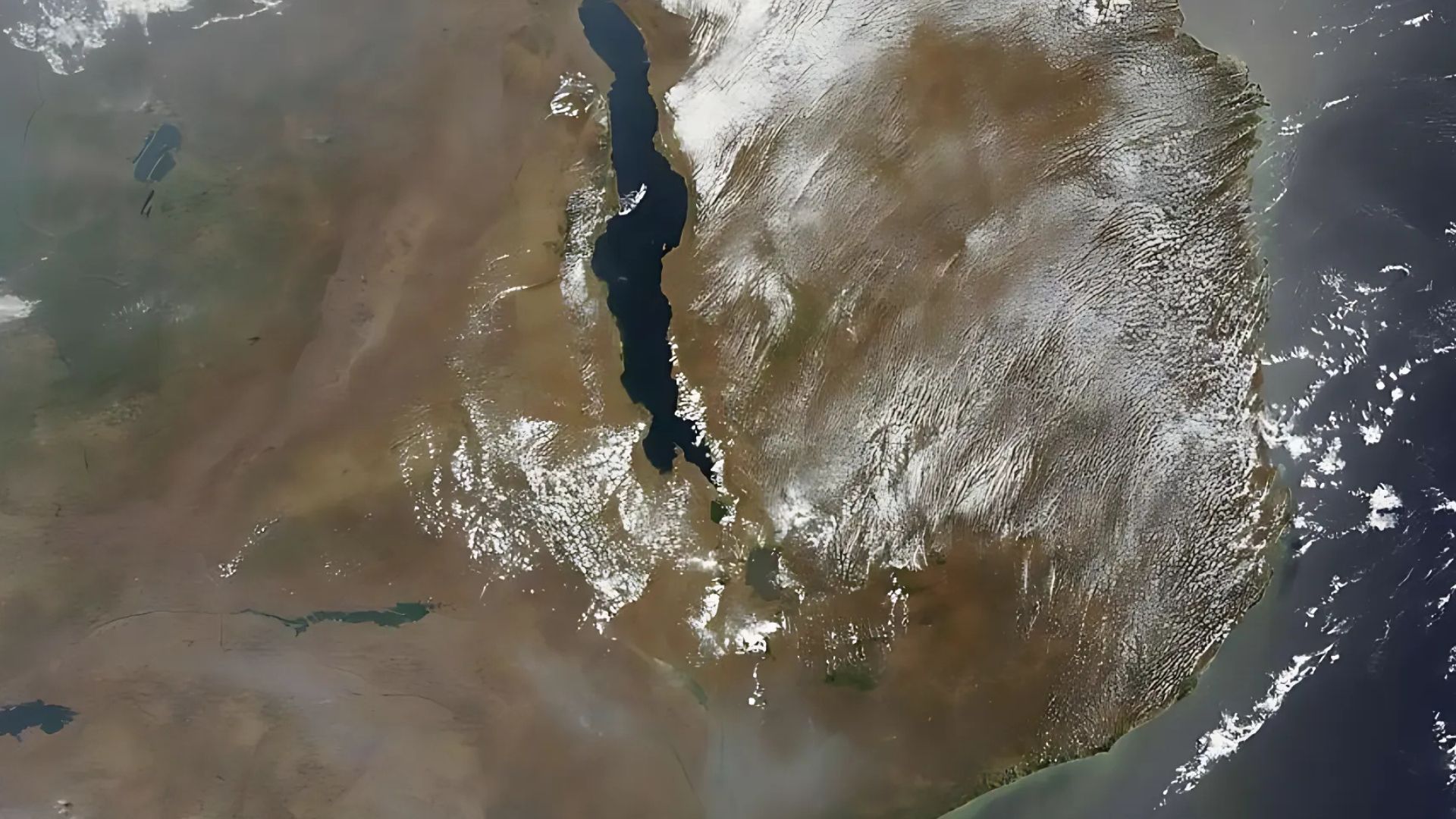 Satellite view of central and southern Africa, showing a large lake, brown land, and clouds.