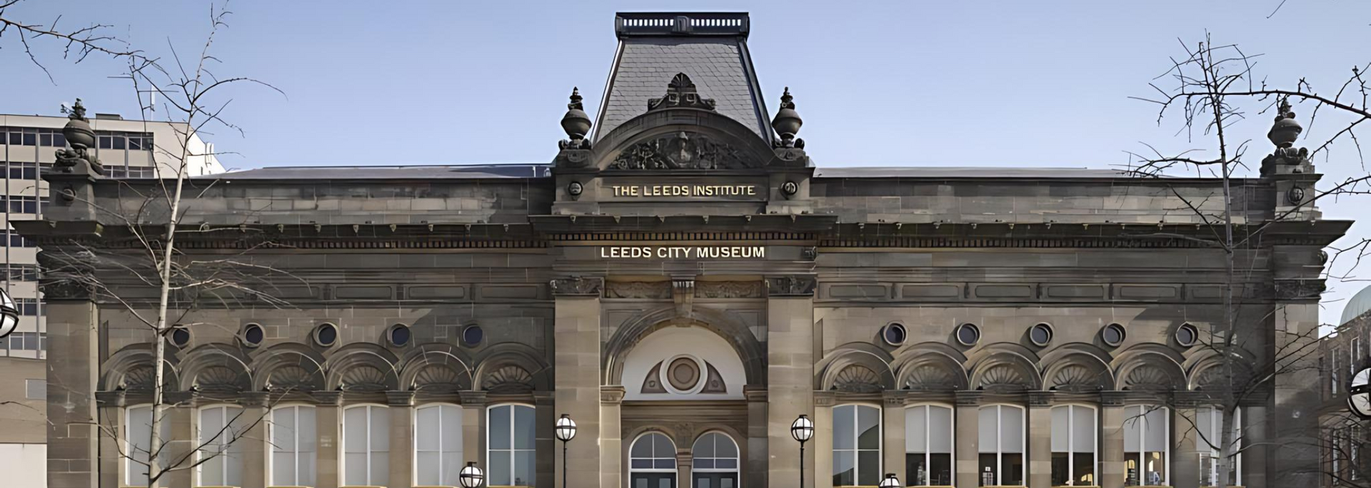 A grand, ornate building with decorative carvings, windows, and a dark roof under a blue sky.