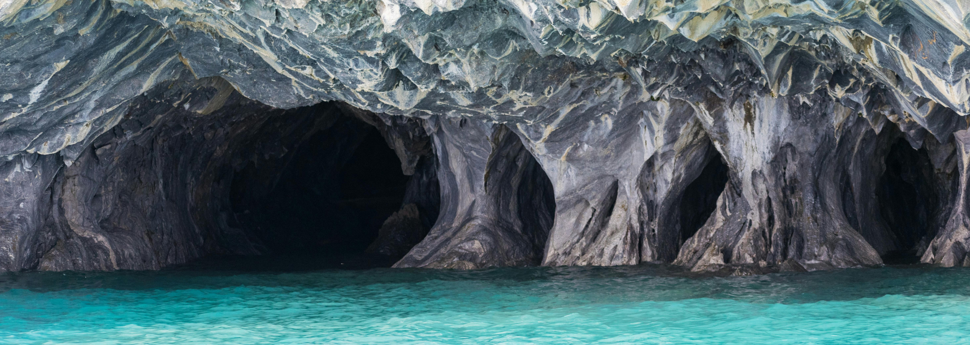 Cave formations along a turquoise body of water.