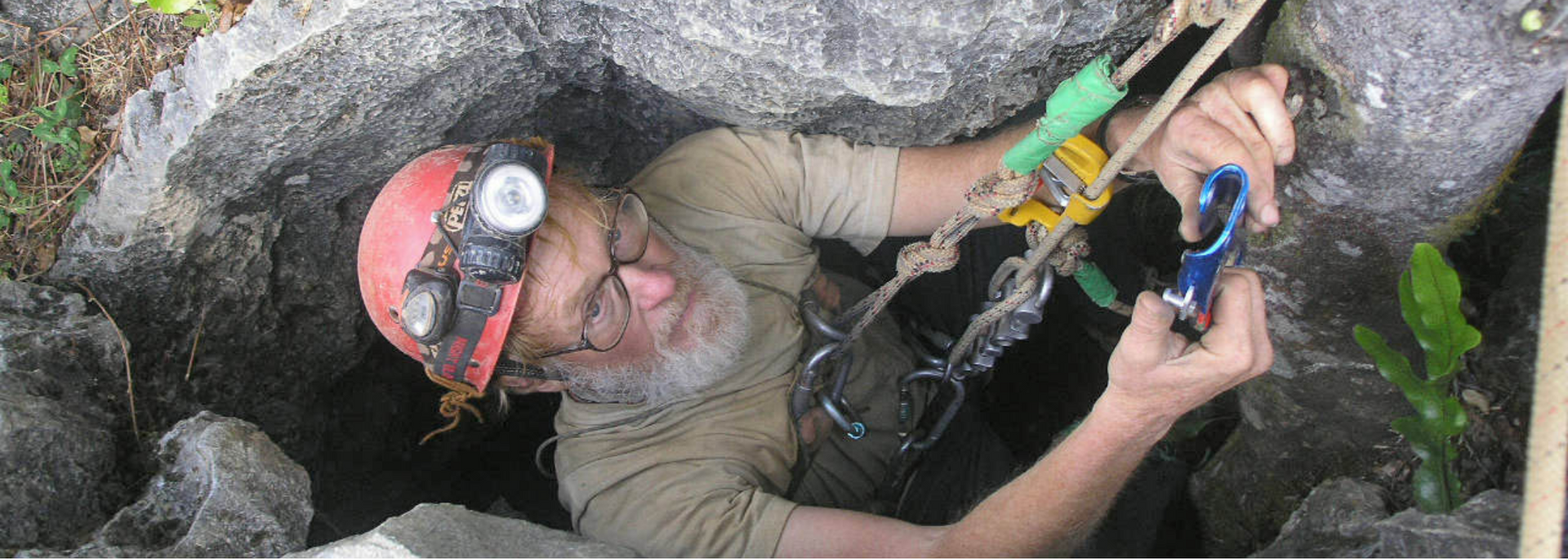 A person wearing a helmet and climbing gear explores a cave.