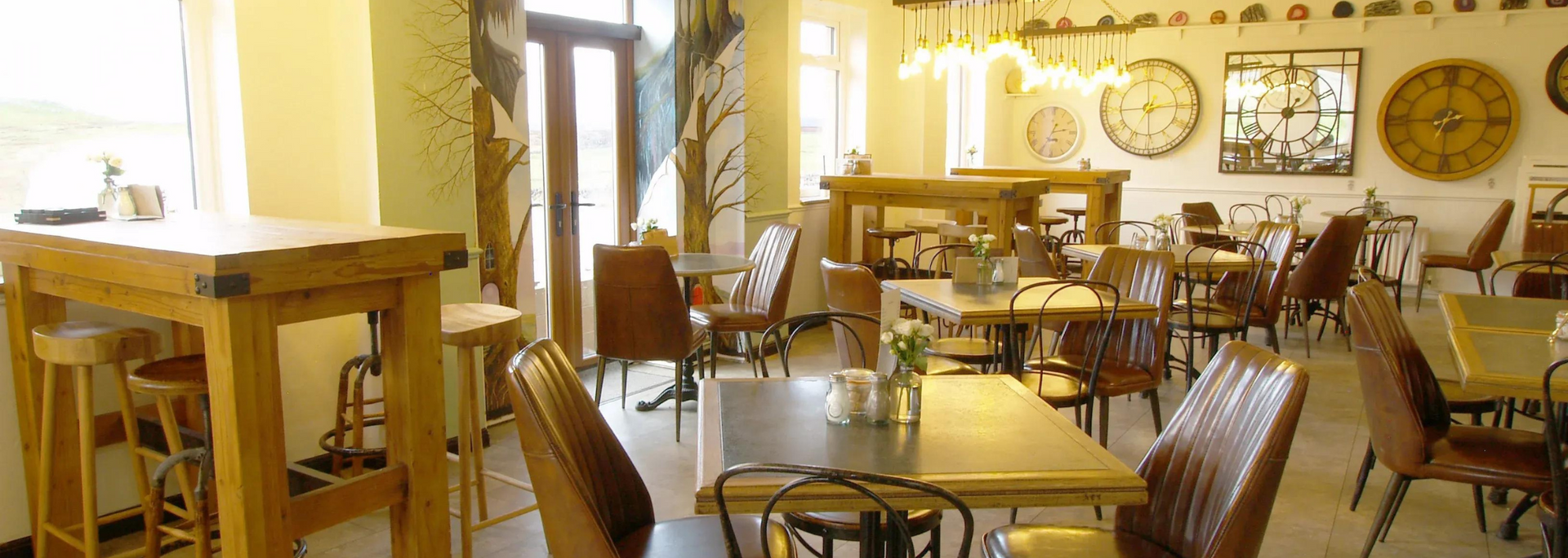 Interior of a cafe with tables, chairs, and decorative wall clocks.