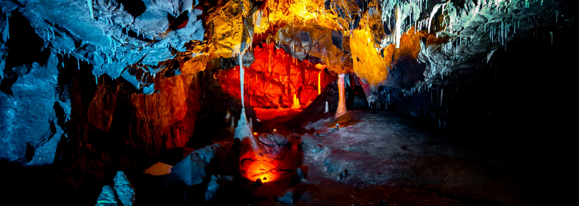 A vibrant cave interior with colorful rock formations illuminated by artificial lights.