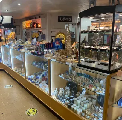 Inside a shop, glass display cases filled with jewelry and small items are arranged along a wall.