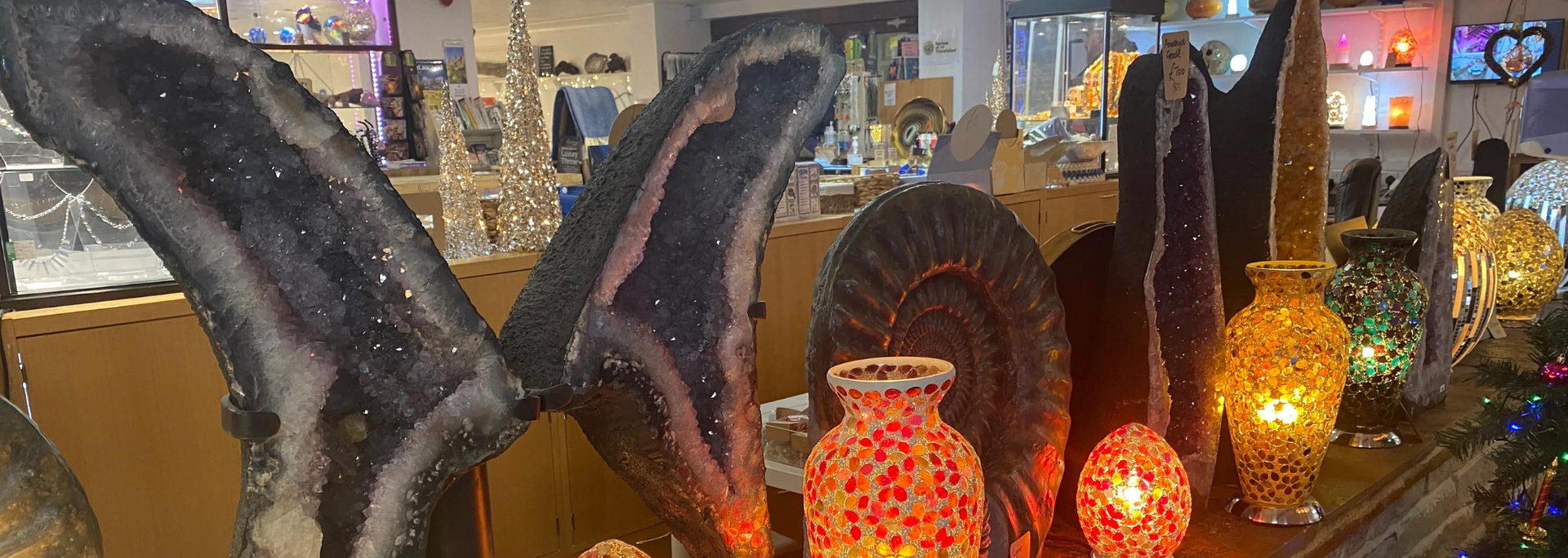 A display of decorative objects, including amethyst geodes, glass vases, and lanterns, in a shop.