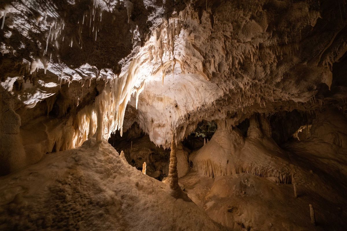 Dimly lit cave interior with rough tan rock walls and a sandy floor