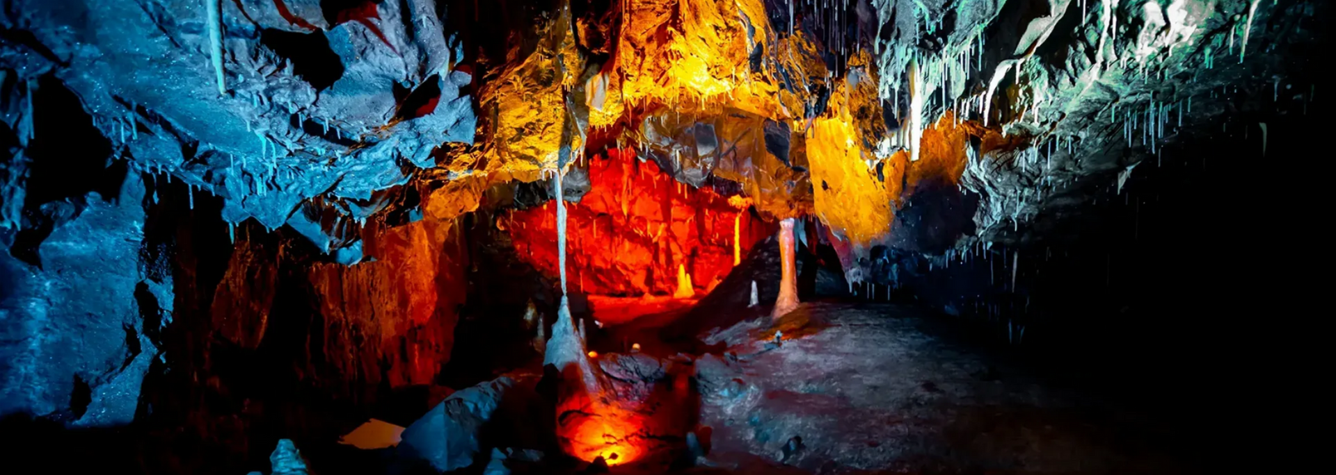 Cave interior with colorful lighting illuminating rock formations and a central red core.
