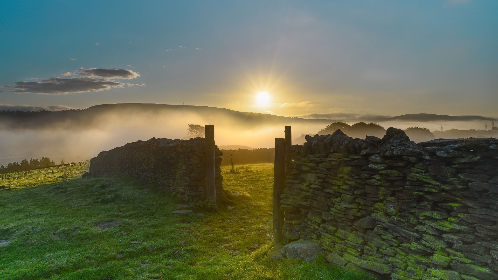 Stone ruins open to a sunrise over a foggy landscape.