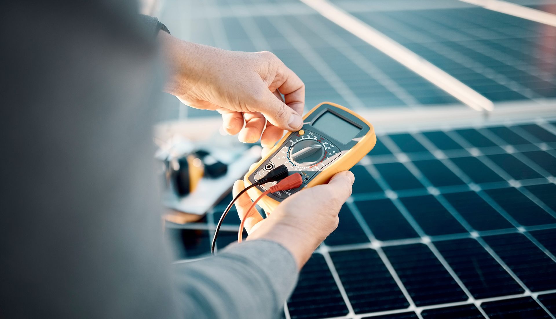 Person using a multimeter to test a solar panel's electrical output.