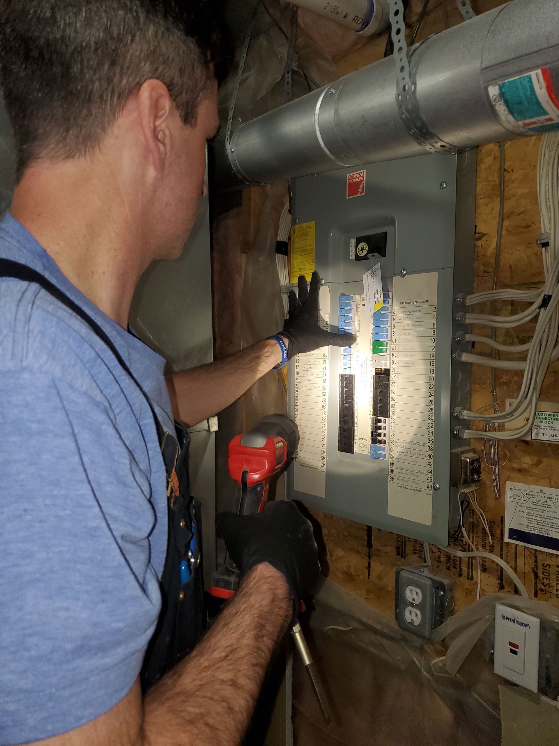 A man is working on an electrical box with a flashlight.