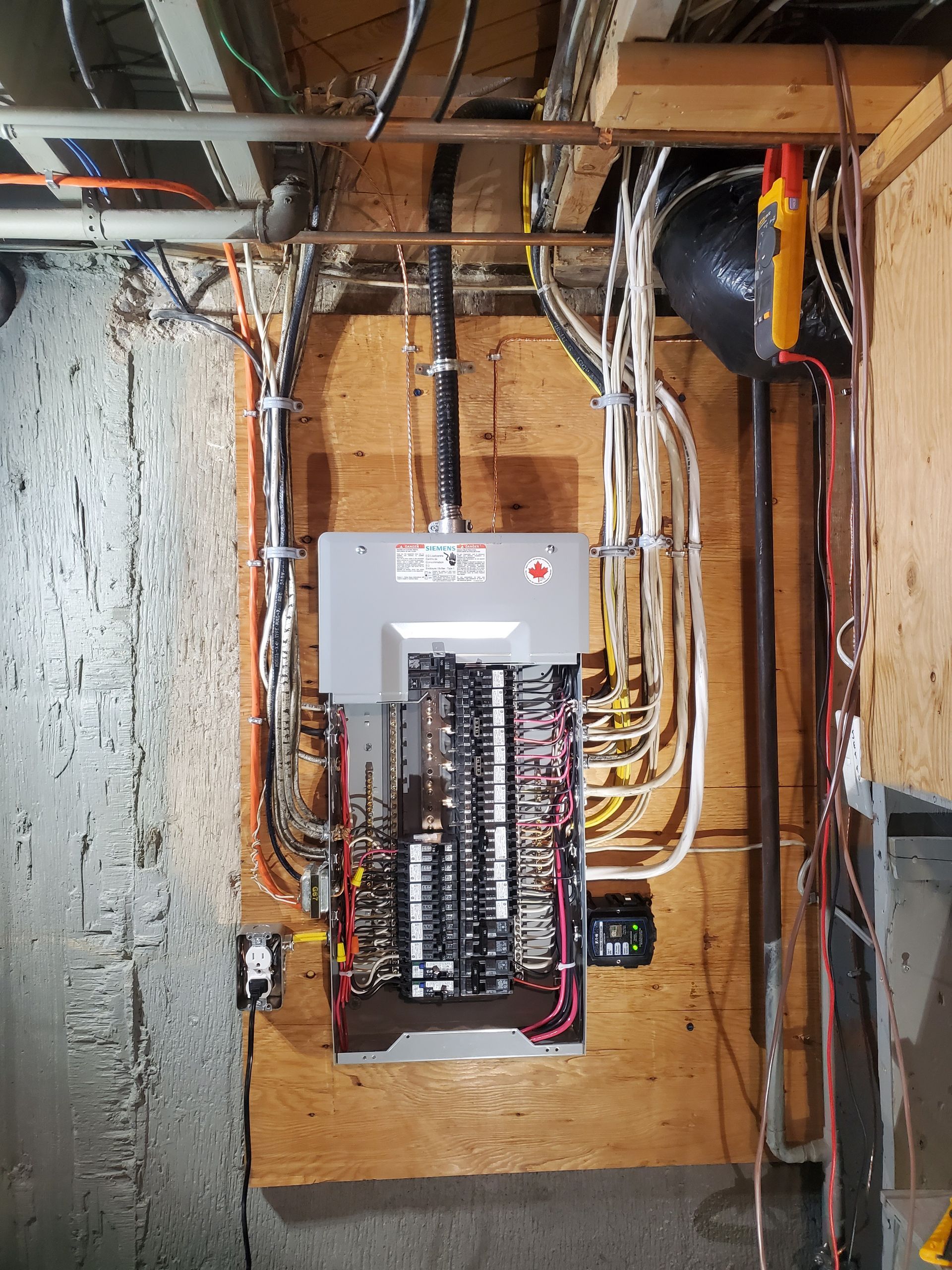 A electrical box is hanging on a wall in a basement.