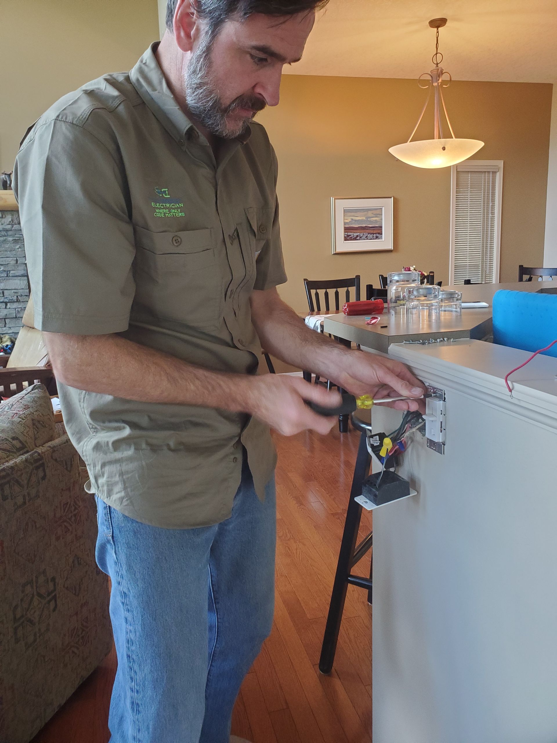 A man is working on a freezer in a living room