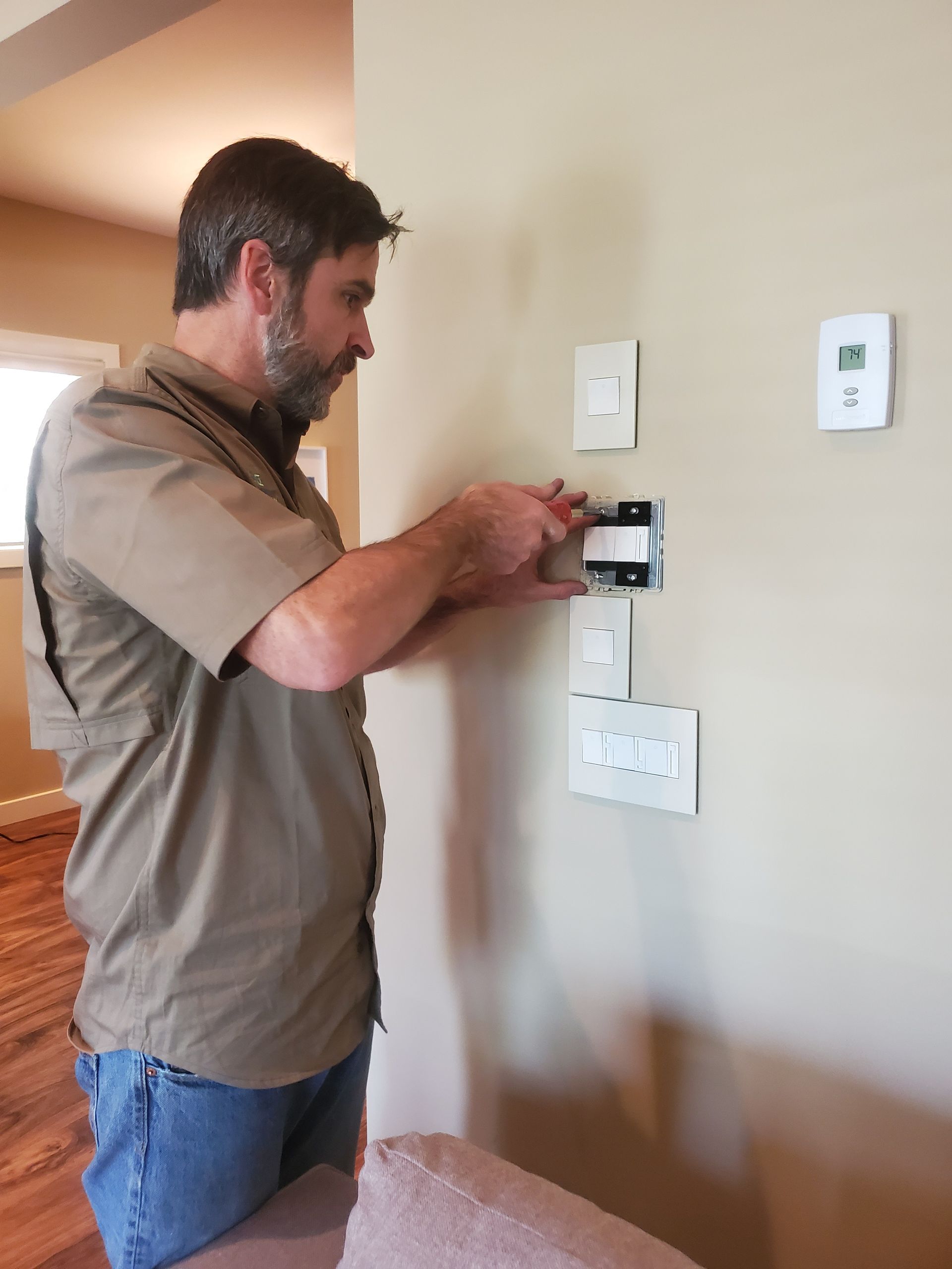 A man is installing a thermostat on a wall.