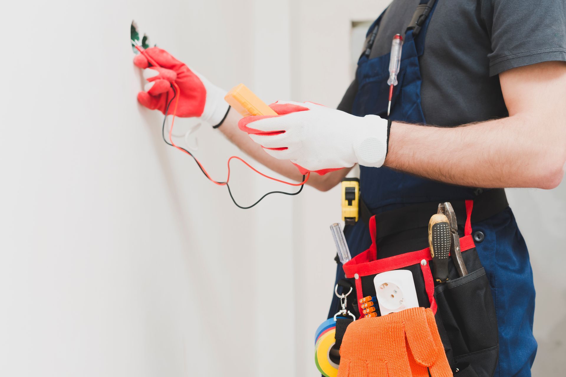 An electrician is working on a wall with a screwdriver.