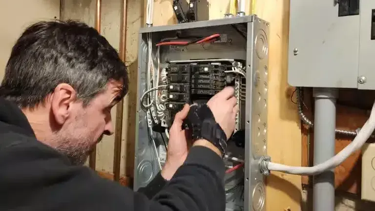 An electrician is working on a wall with a voltage meter.