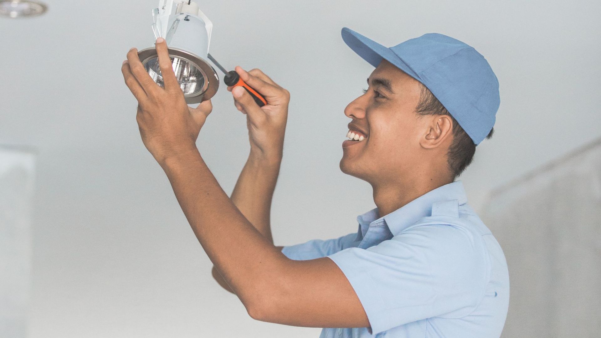 A man is installing a light bulb in a ceiling.