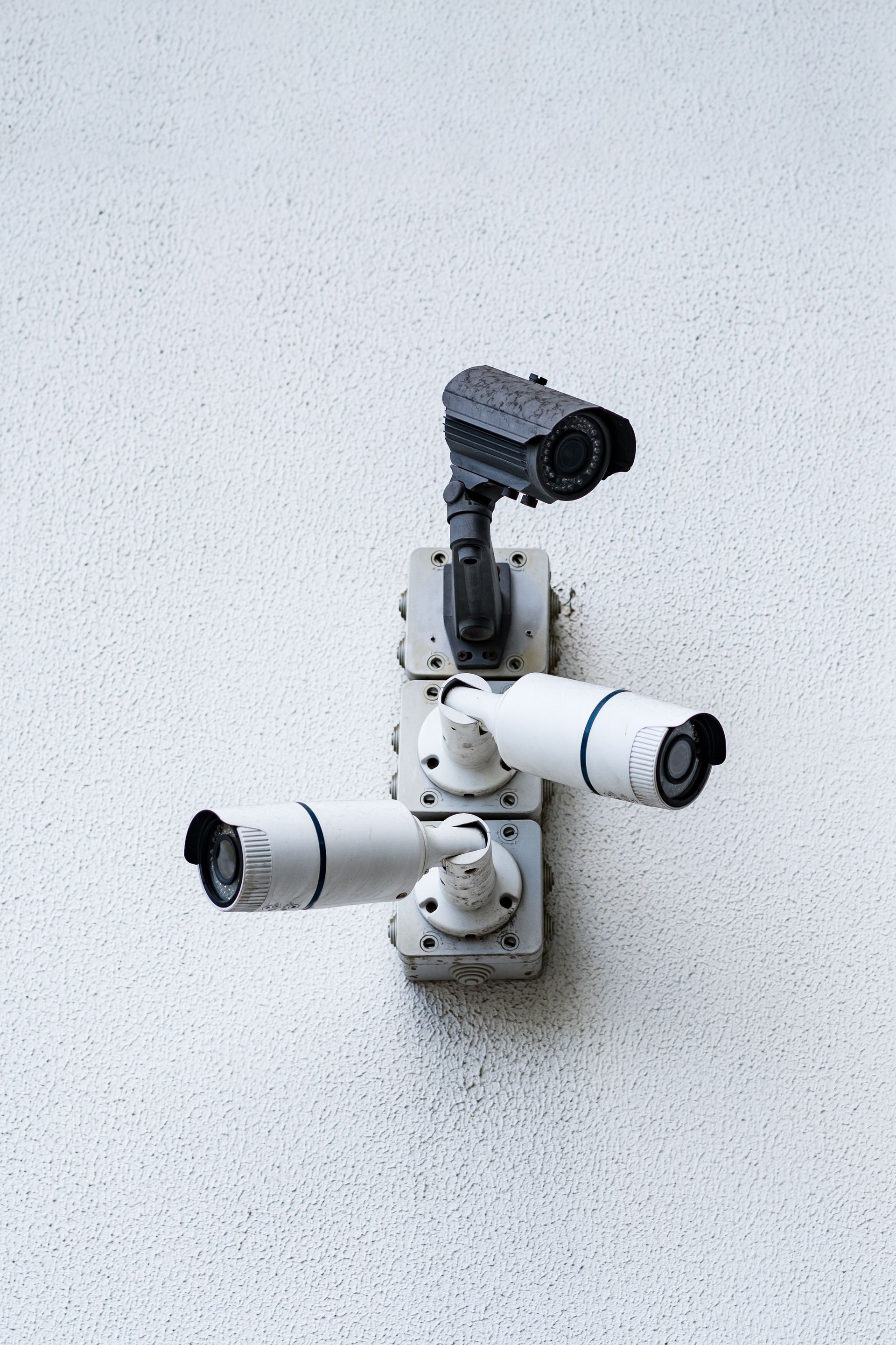 Three security cameras are mounted on a white wall.