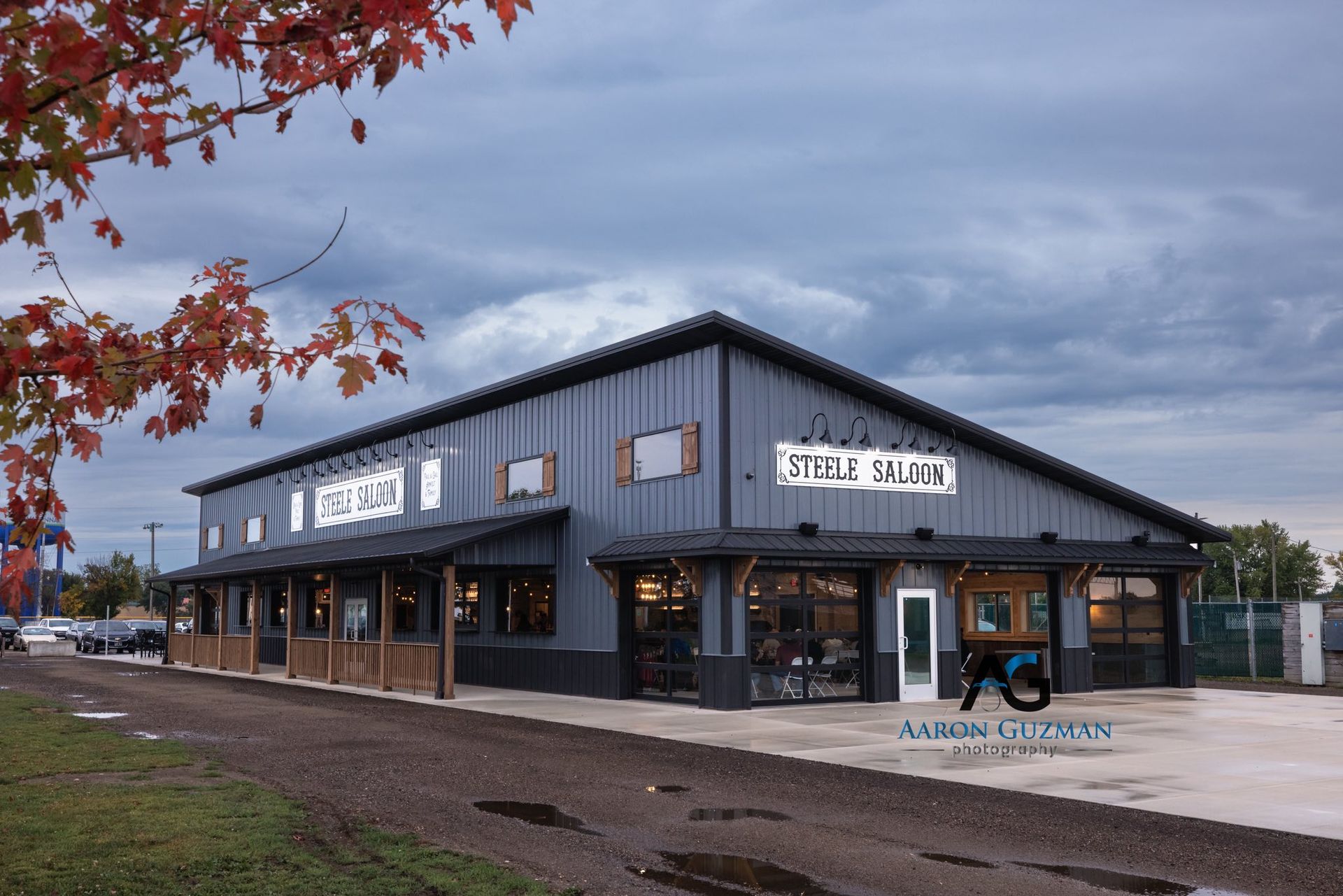 A modern, dark-gray metal building with a covered wooden porch, labeled 