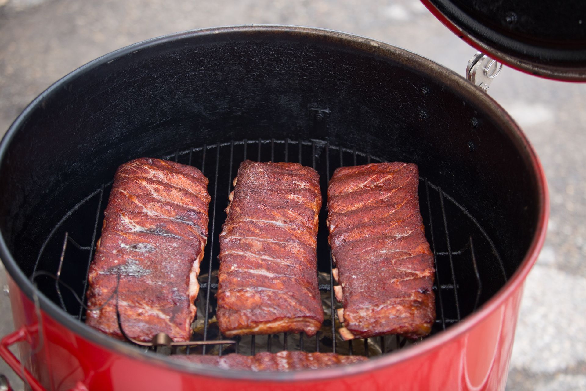 Hands holding a sliced, cooked brisket with visible bark and pink smoke ring, on a butcher paper surface.