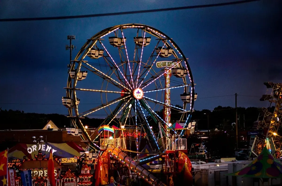 Ferris wheel at night, illuminated with colorful lights; carnival setting.