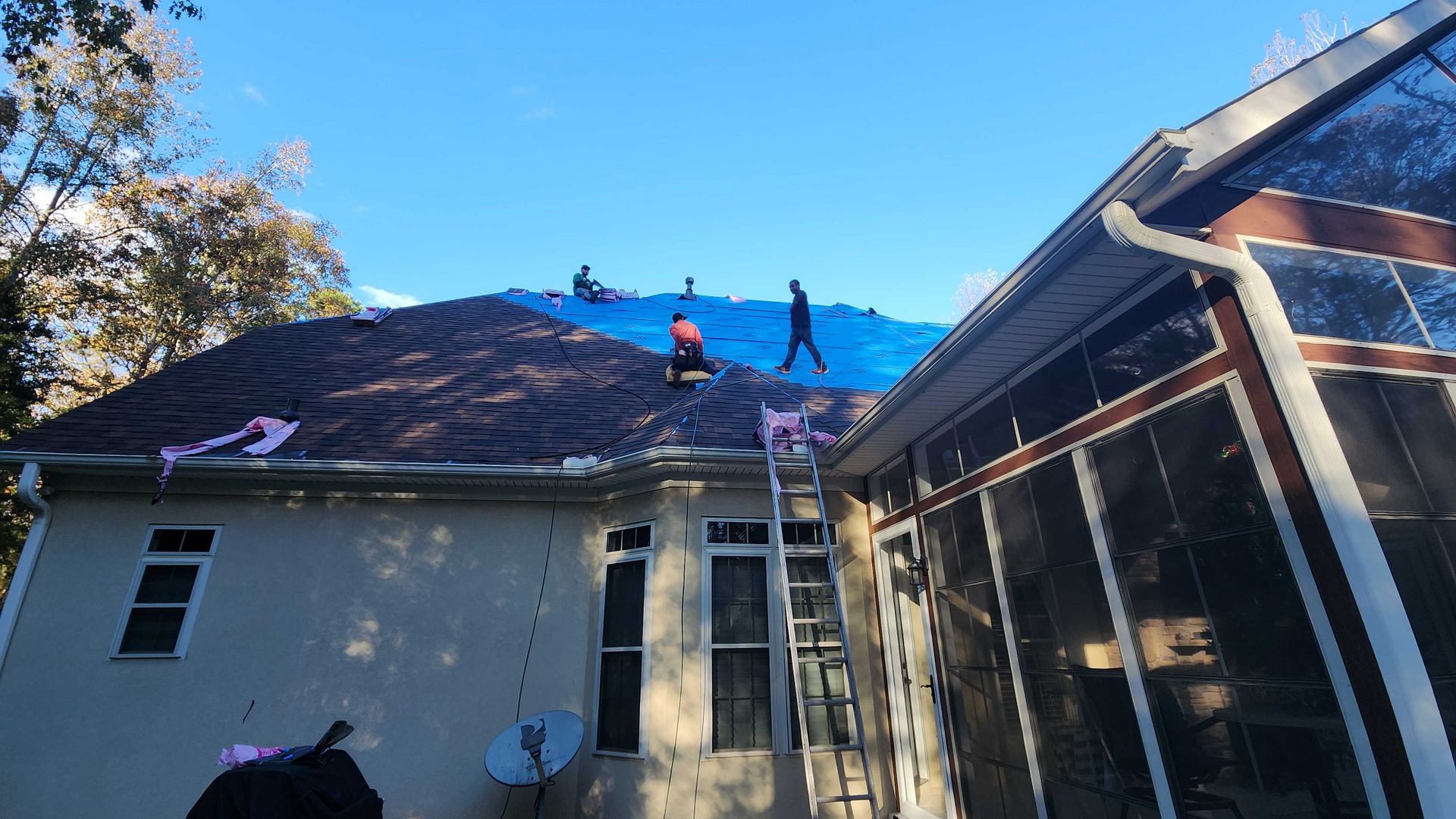 A group of people are working on the roof of a house.