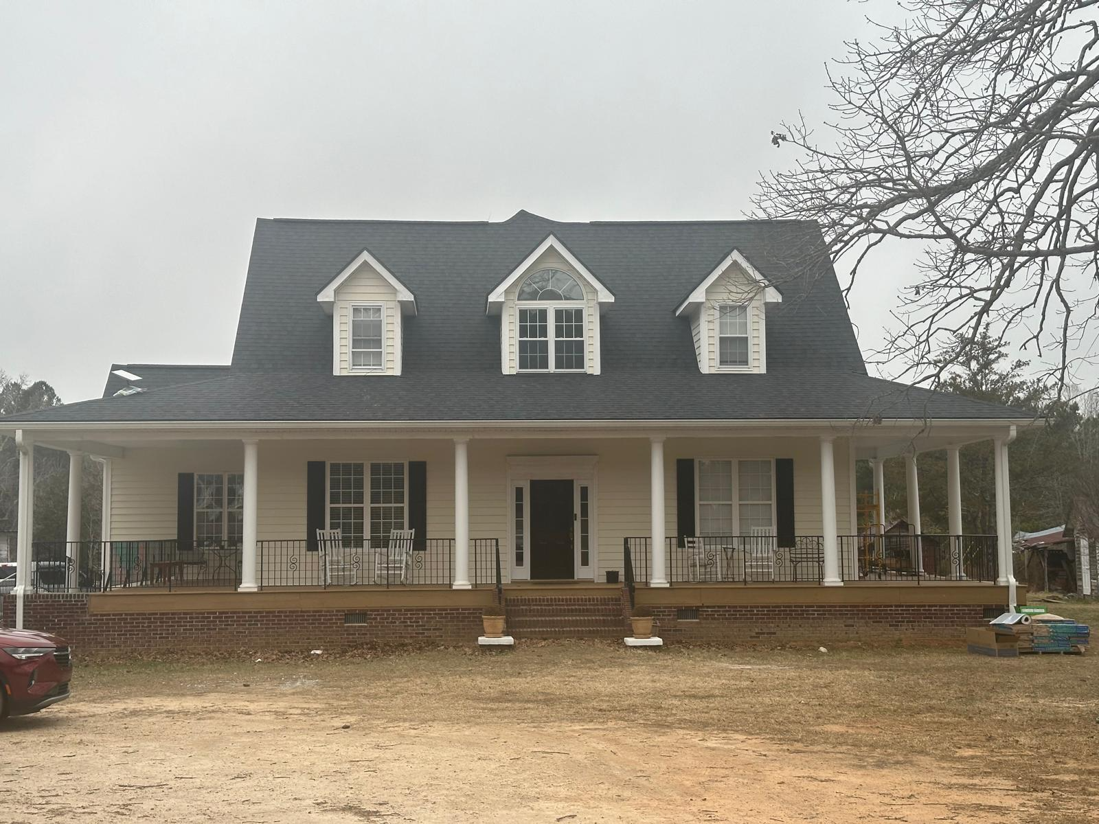 A large white house with a black roof and a large porch