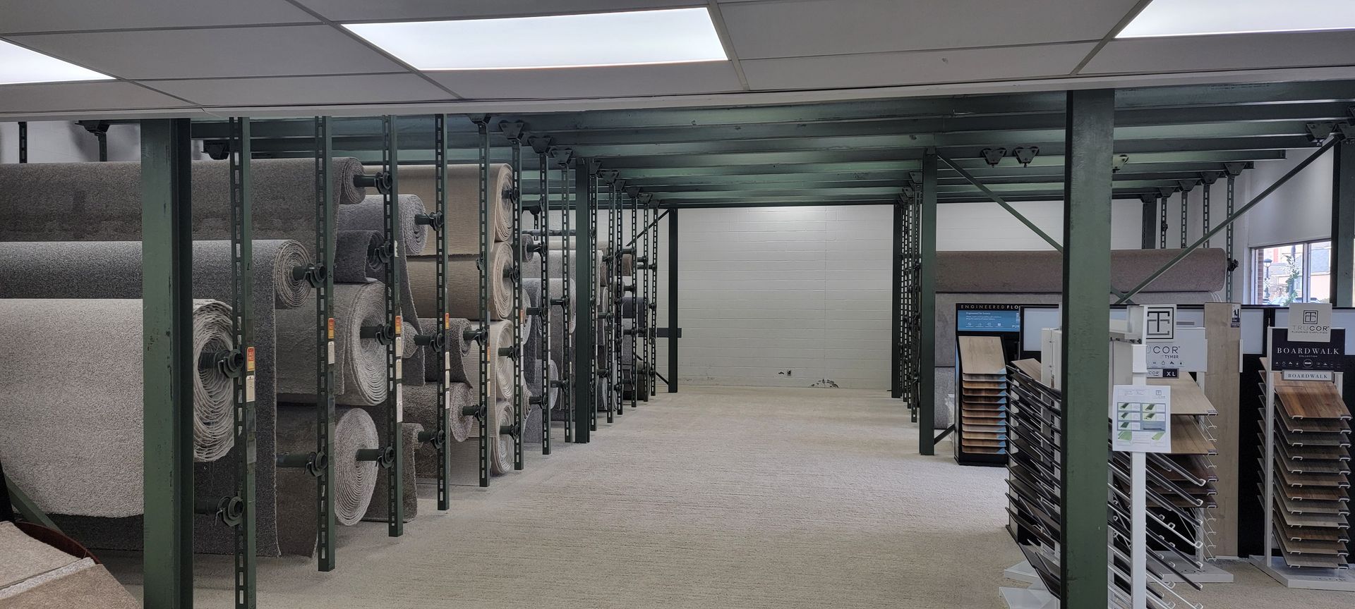 Interior of a carpet store with rolls of carpet on racks and a person working. Interior of a carpet store with rolls of carpet on racks and a person working.
