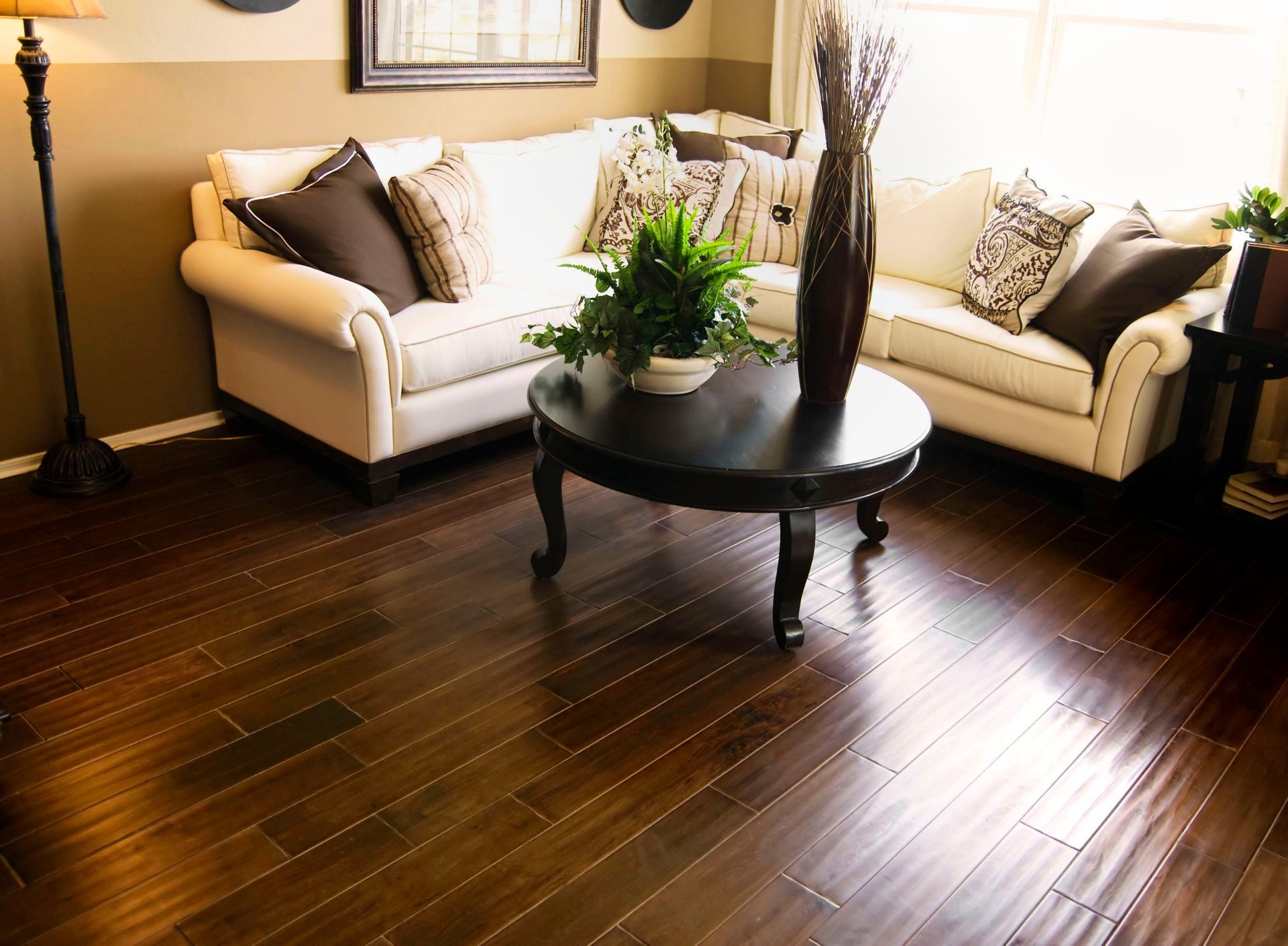 Living room with hardwood floors, white sectional sofa, round coffee table, and tall vase.