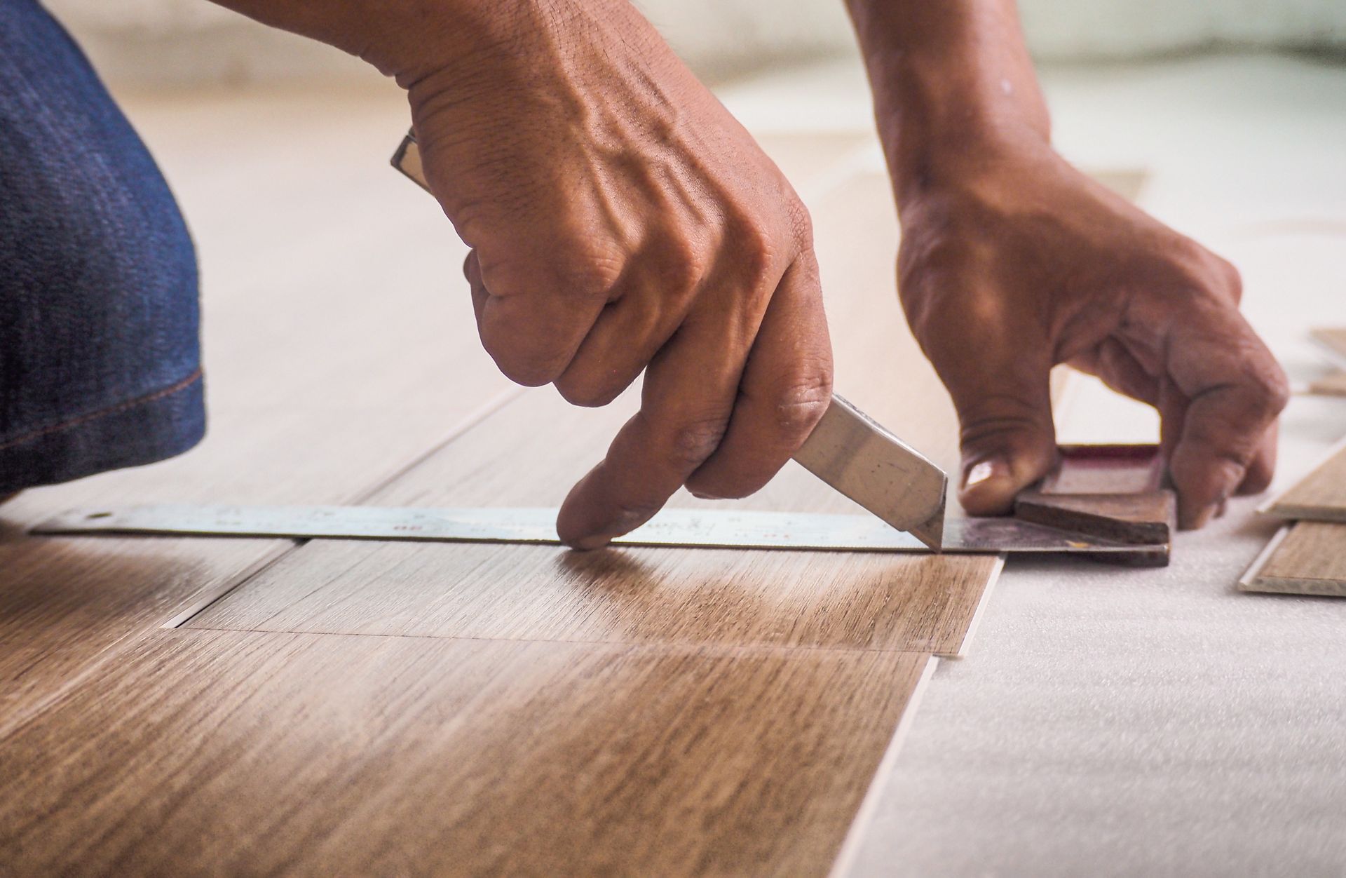 Person cutting wood flooring with a knife and ruler. Person cutting wood flooring with a knife and ruler.