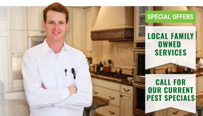 A man in a white shirt is standing in a kitchen with his arms crossed.