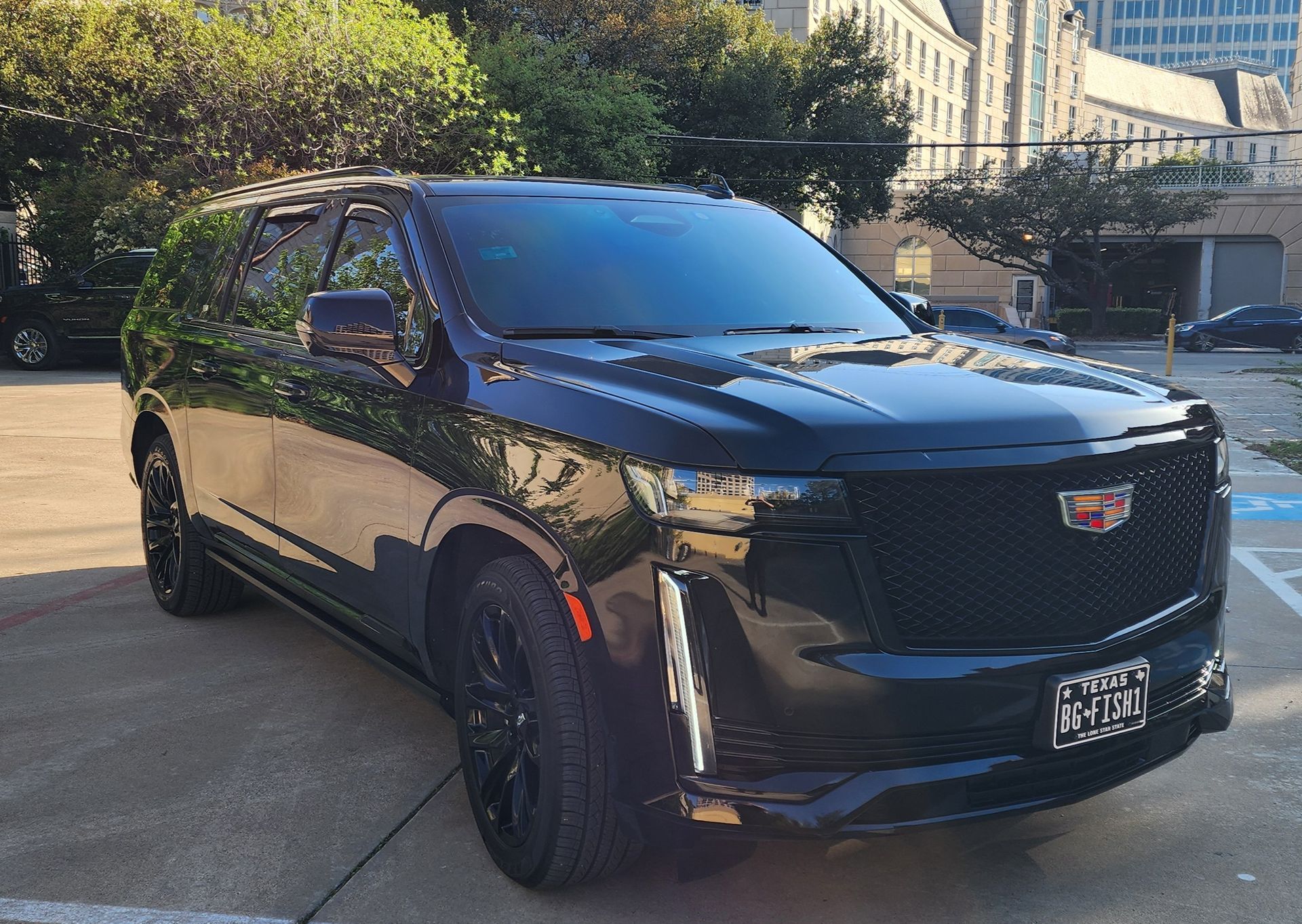 A black cadillac escalade is parked in a parking lot.