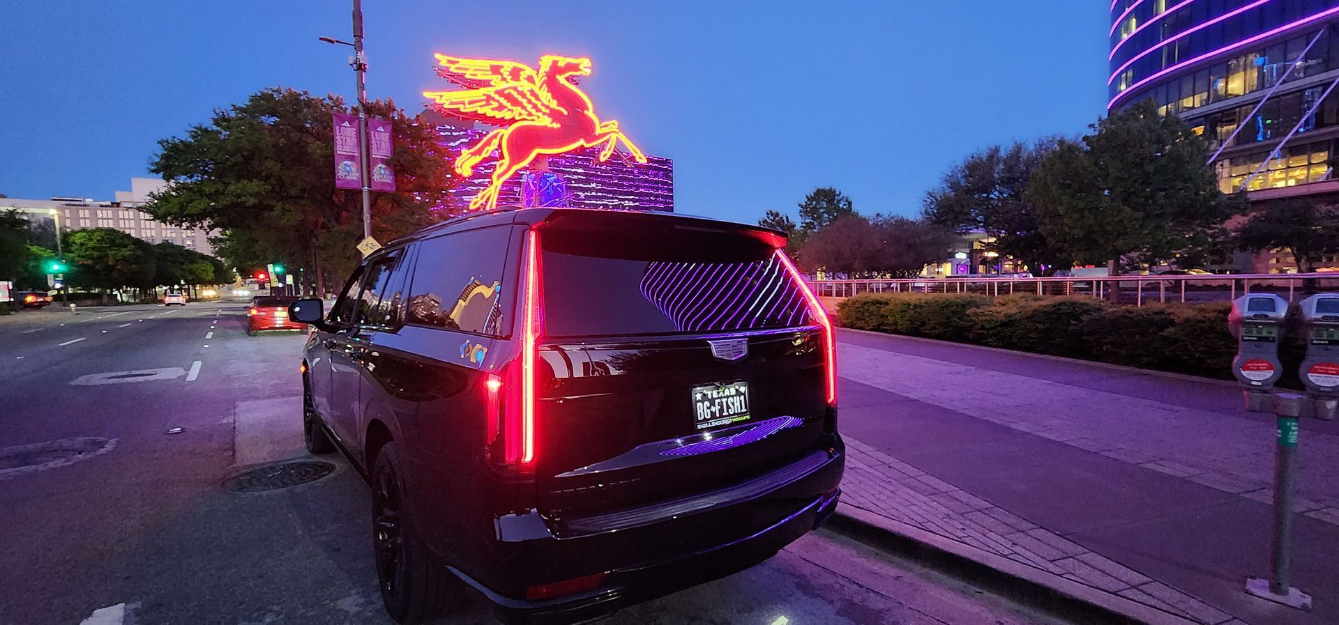A black suv is parked on the side of the road in front of a building with christmas lights on it.