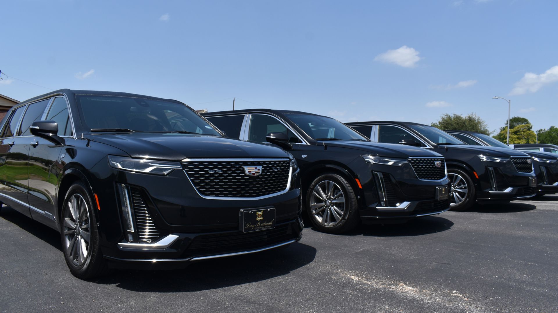 A row of black cars are parked in a parking lot.