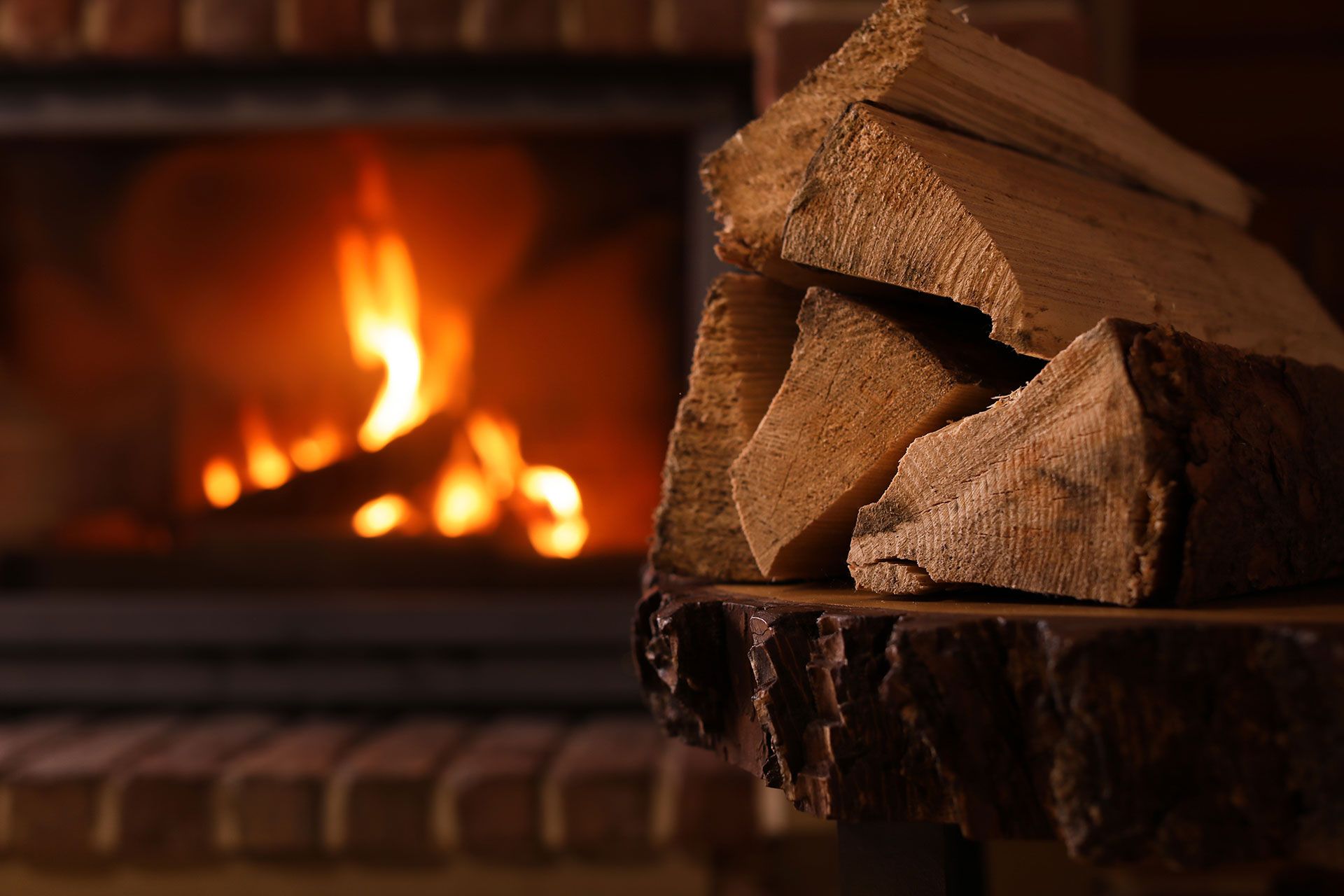 stack of firewood next to a lit fireplace