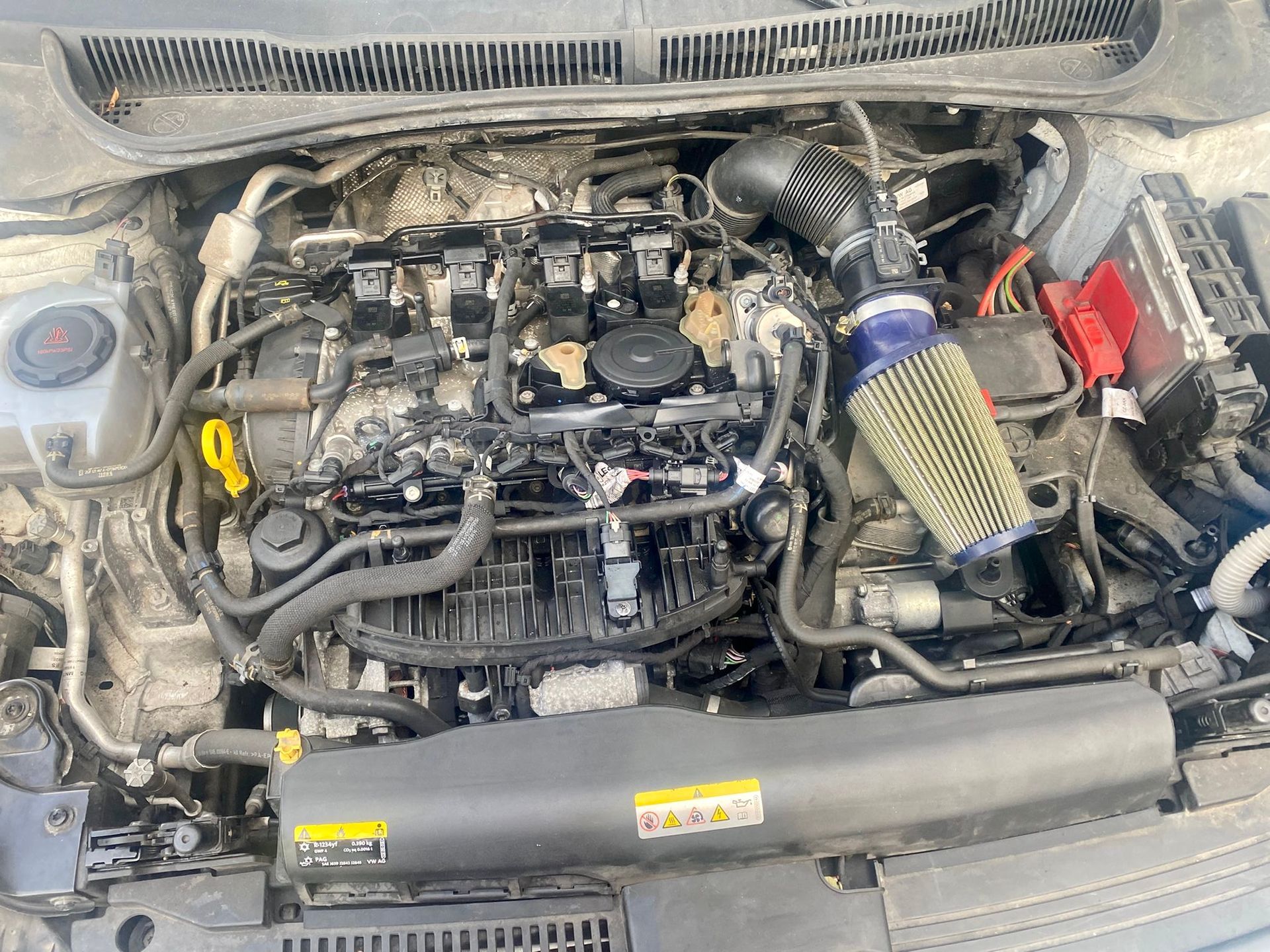 Un primo piano del motore di un'auto con il cofano aperto.