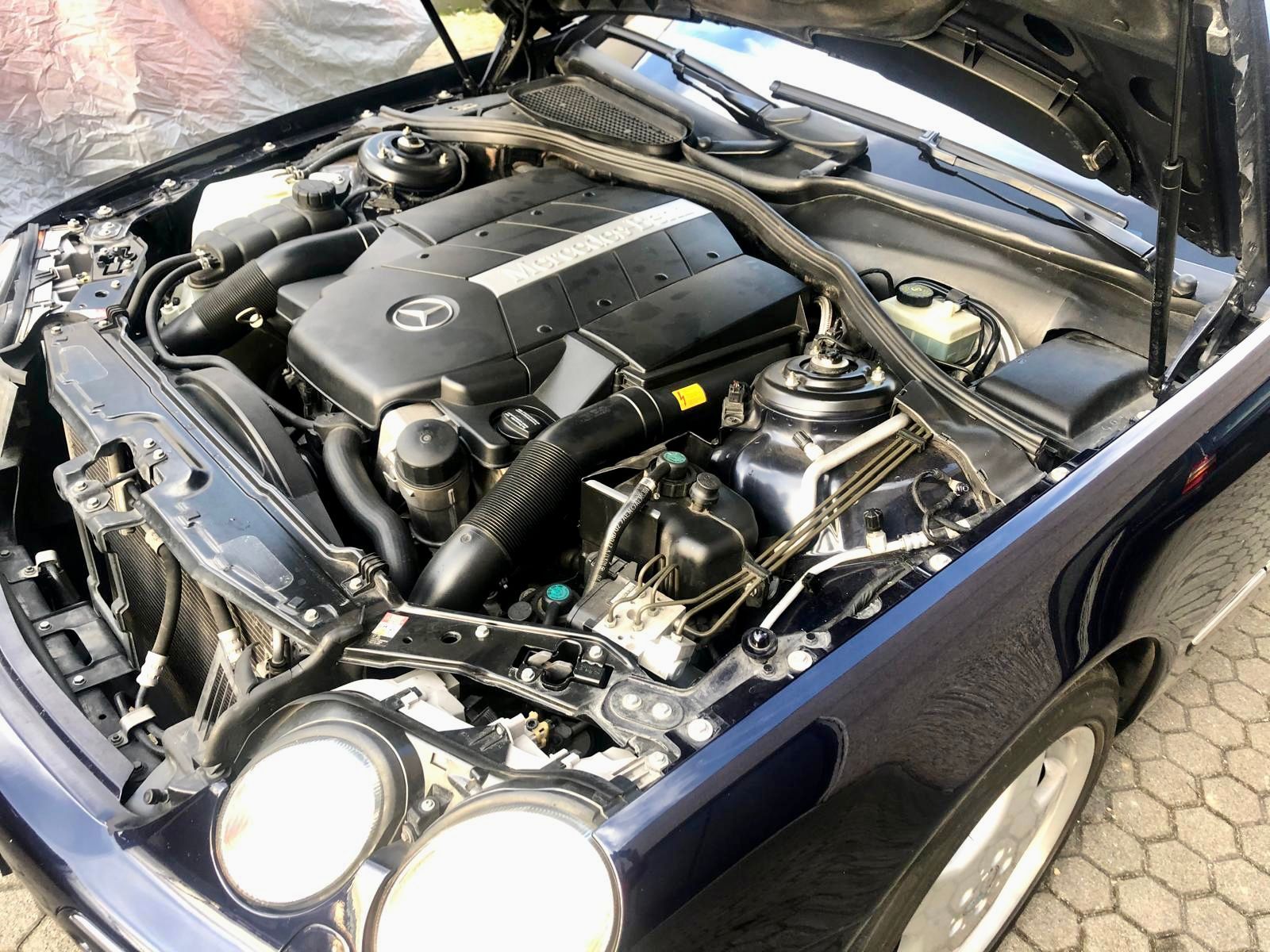 Il motore di un'auto blu è mostrato con il cofano aperto.