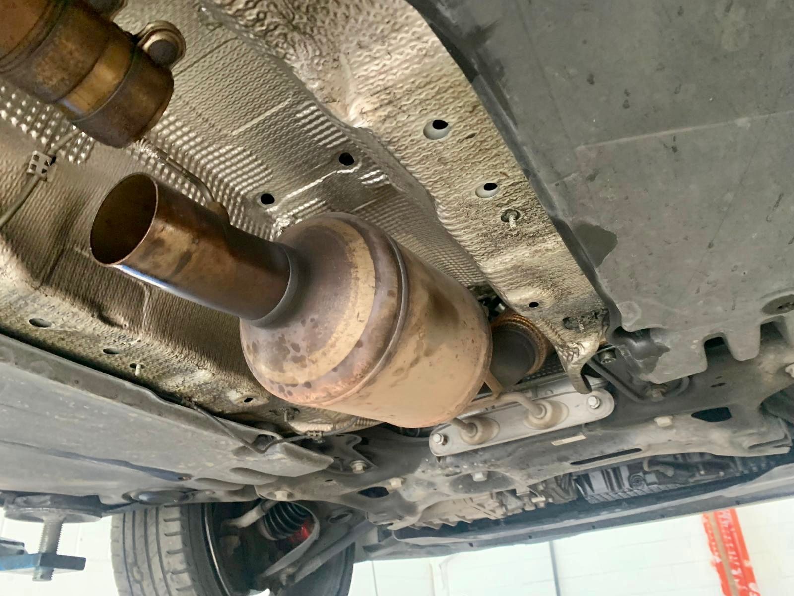 Un primo piano della parte inferiore di un'auto con convertitore catalitico.