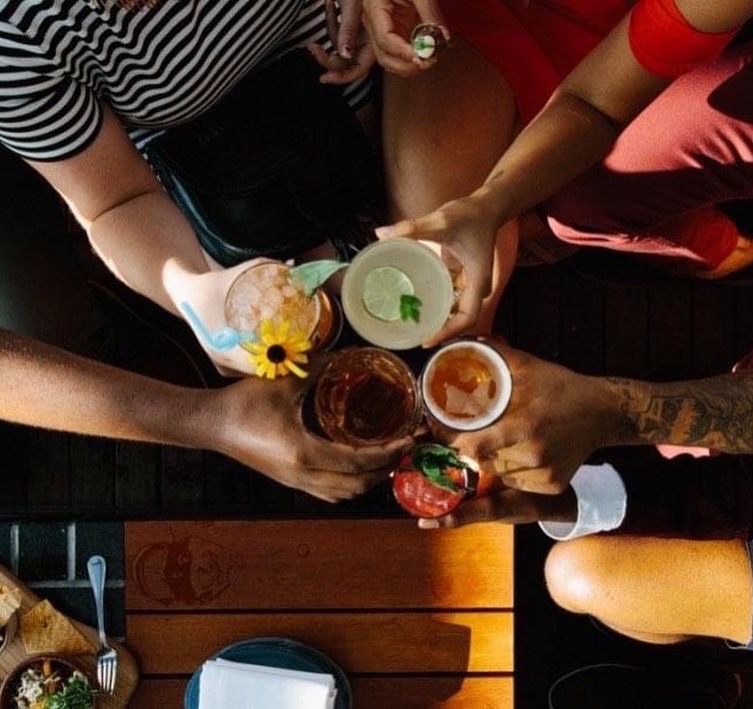 A group of people are sitting at a table toasting with drinks