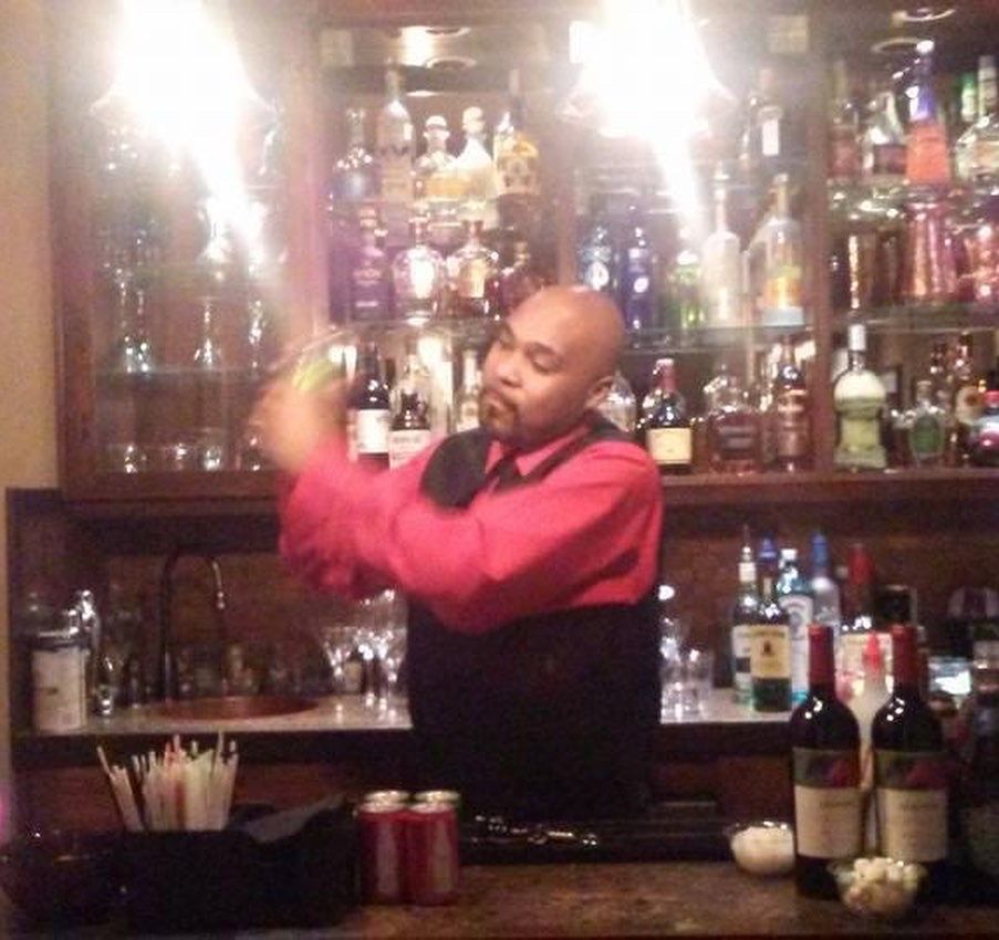 A man in a red shirt is standing behind a bar
