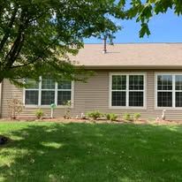 Beige house with multiple windows and a green lawn.