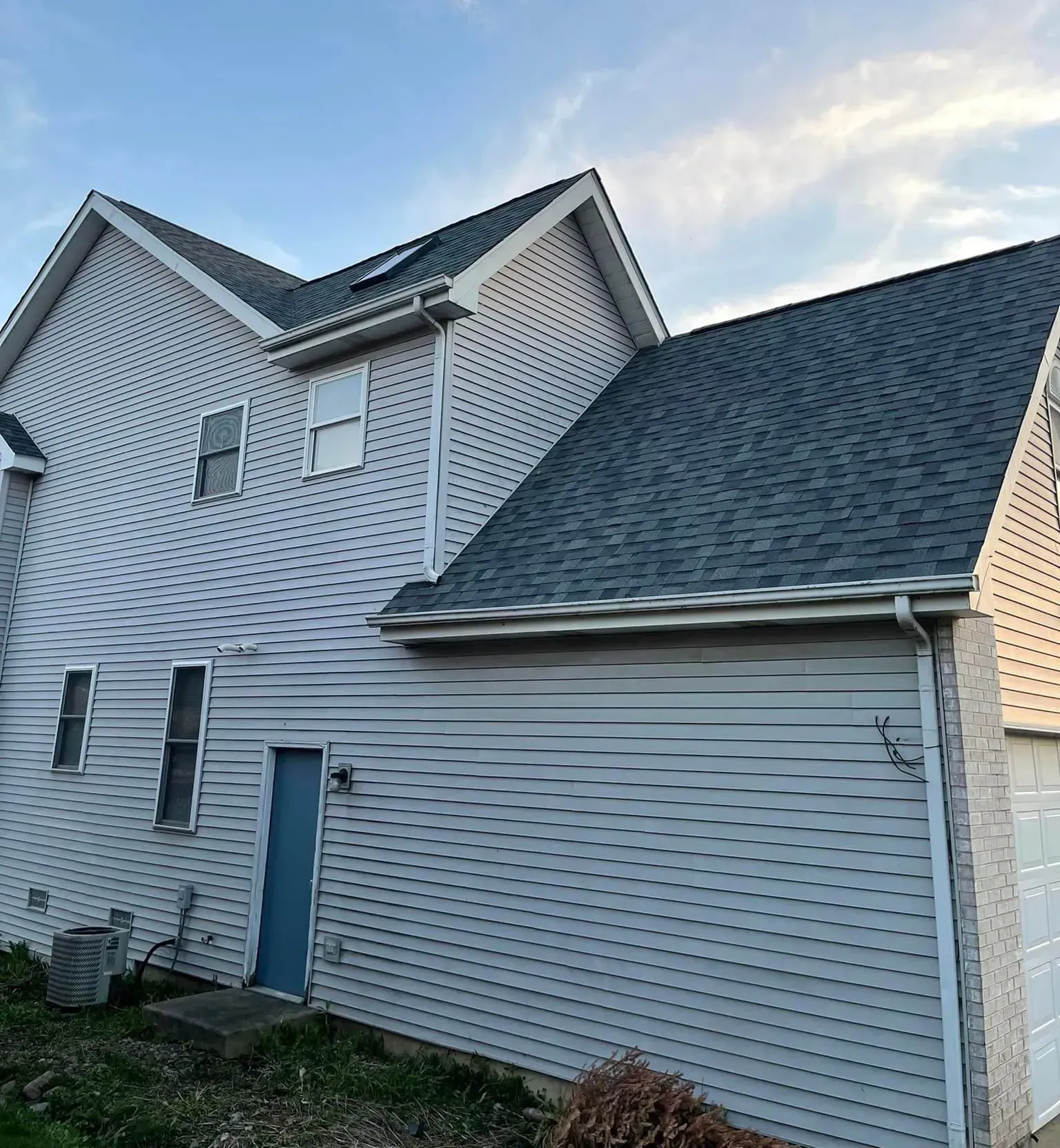 Gray house with matching roof against a blue sky.