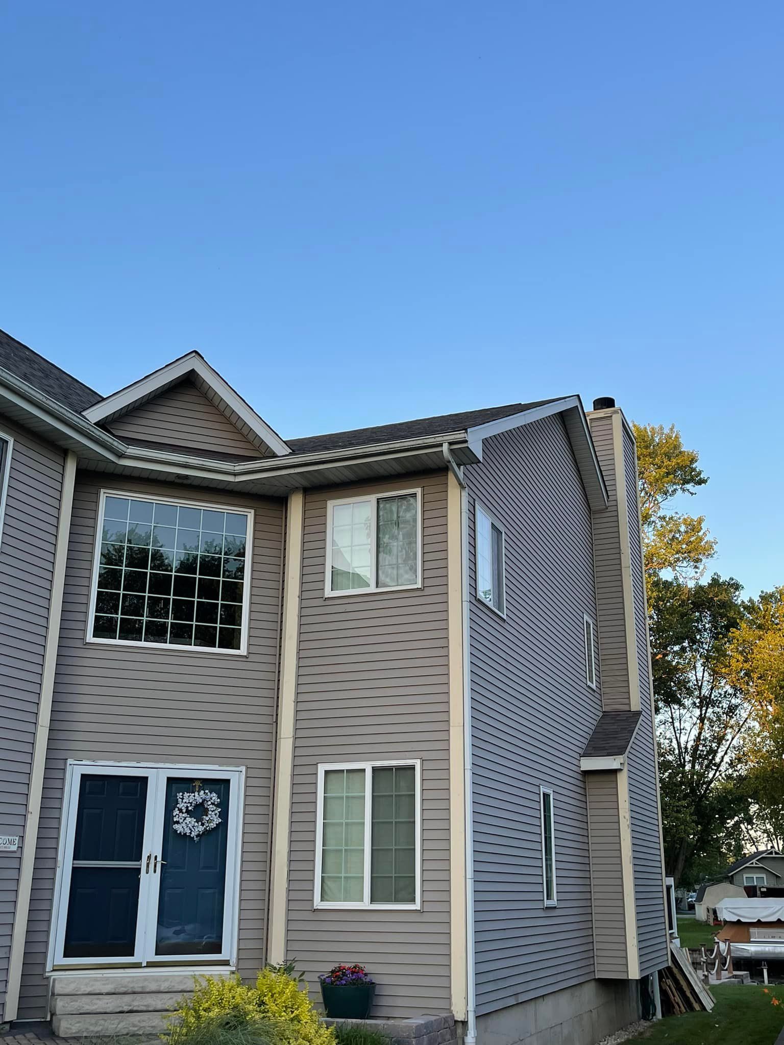 Gray two-story townhouse with swirling pattern on side under a clear, blue sky.