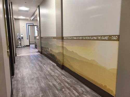 Hallway with wood-look flooring and a mural of a mountain range. White and gray walls, doors.