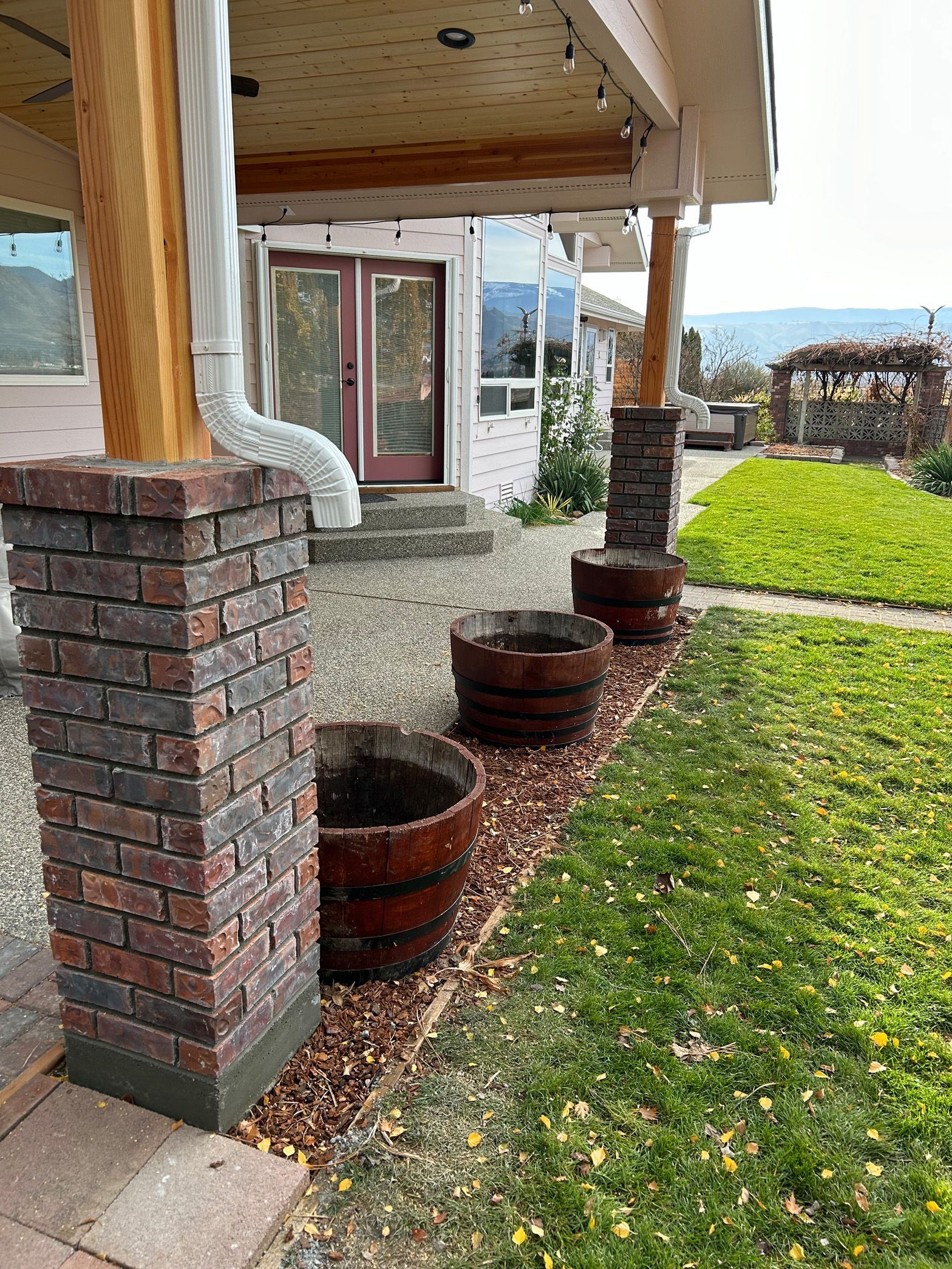 A house with a brick porch and a row of barrels in front of it.