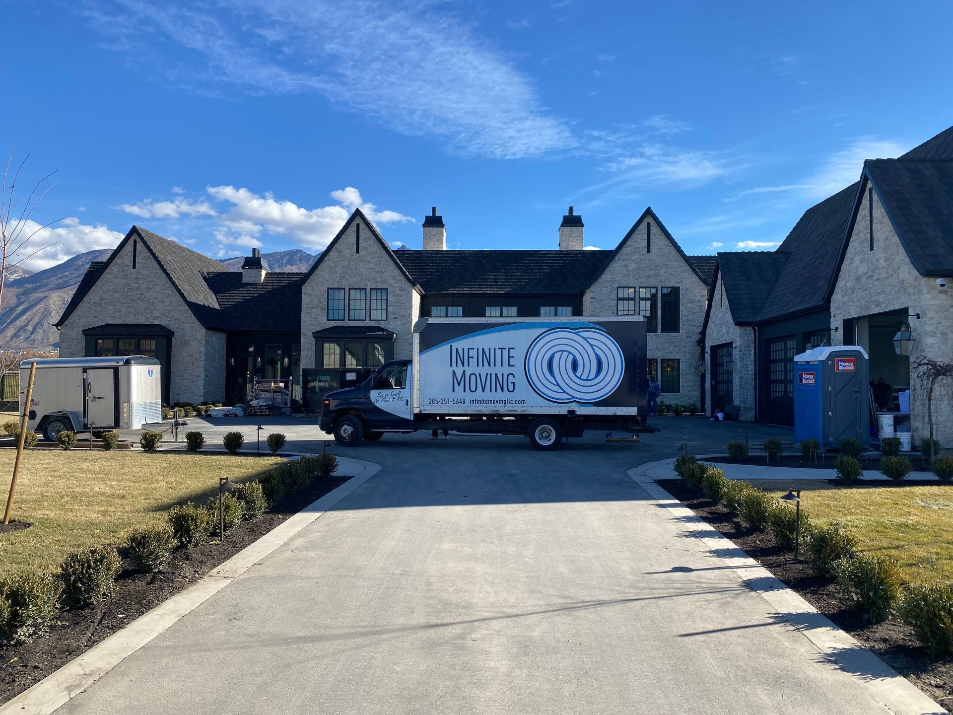 A moving truck is parked in front of a large house.