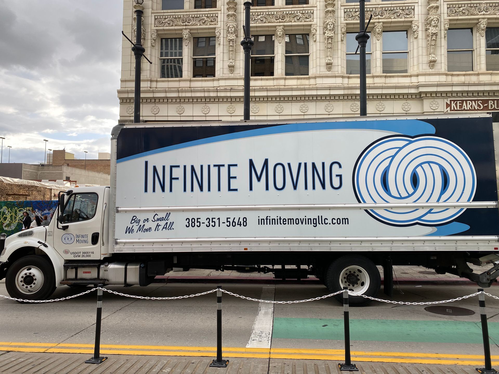 White Infinite Moving truck parked in front of a building.