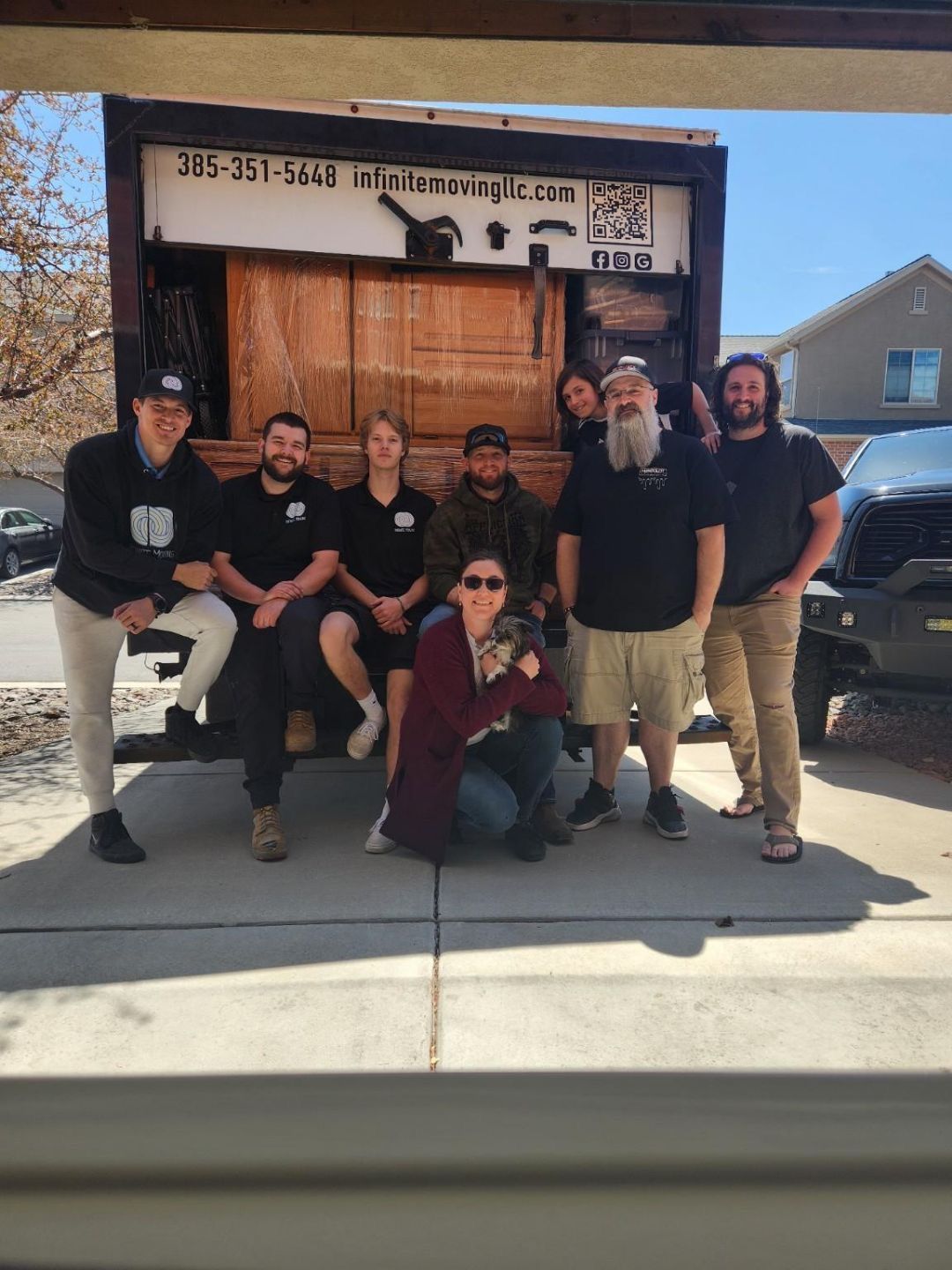 A group of people are posing for a picture in front of a moving truck.