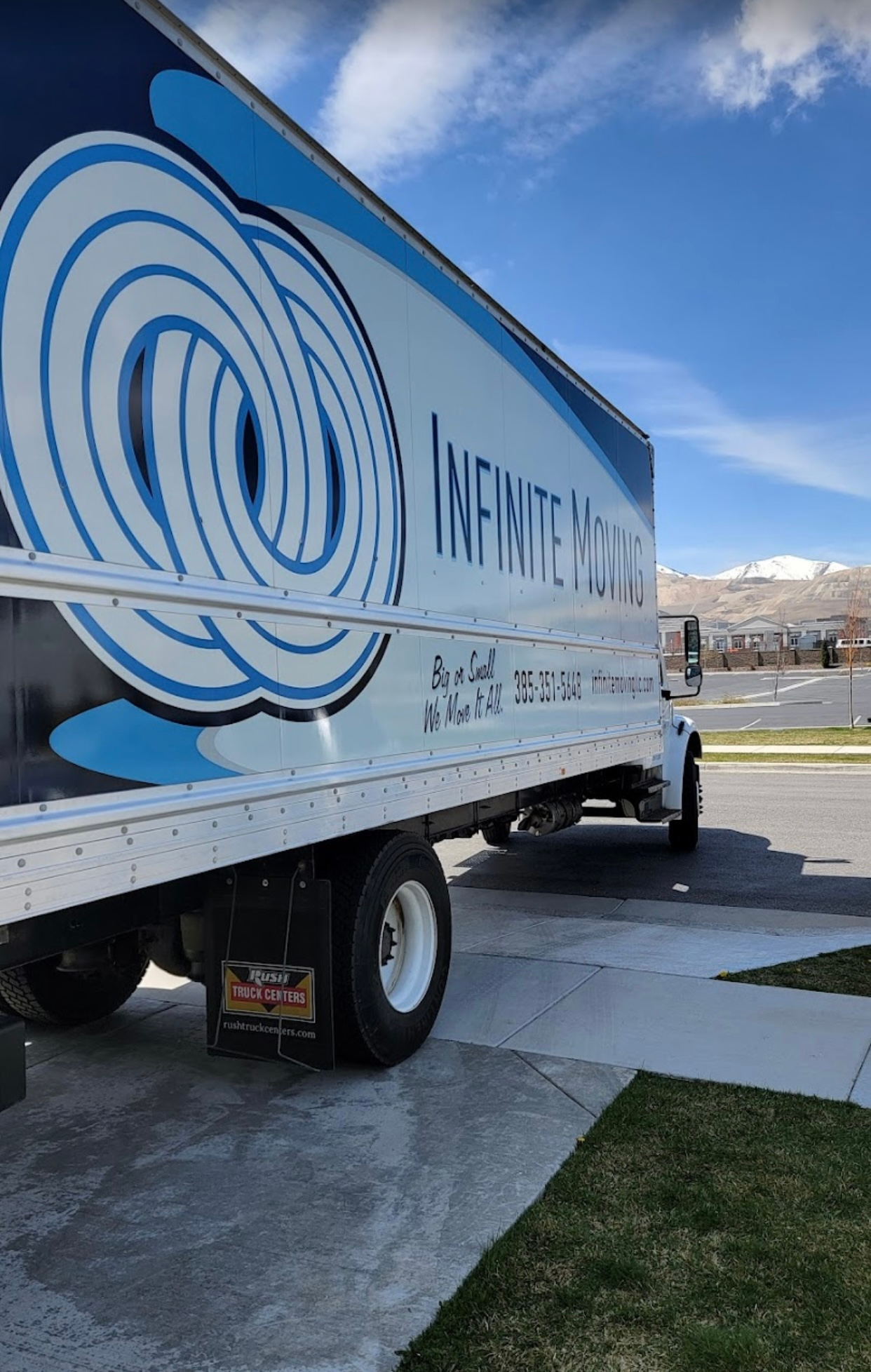 A blue and white moving truck is parked in a driveway.
