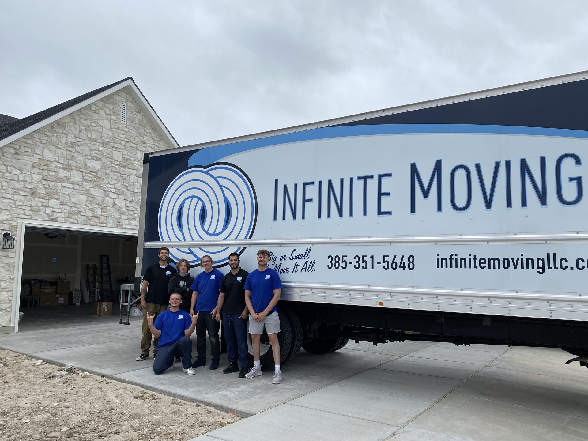 A group of men are posing in front of a moving truck.